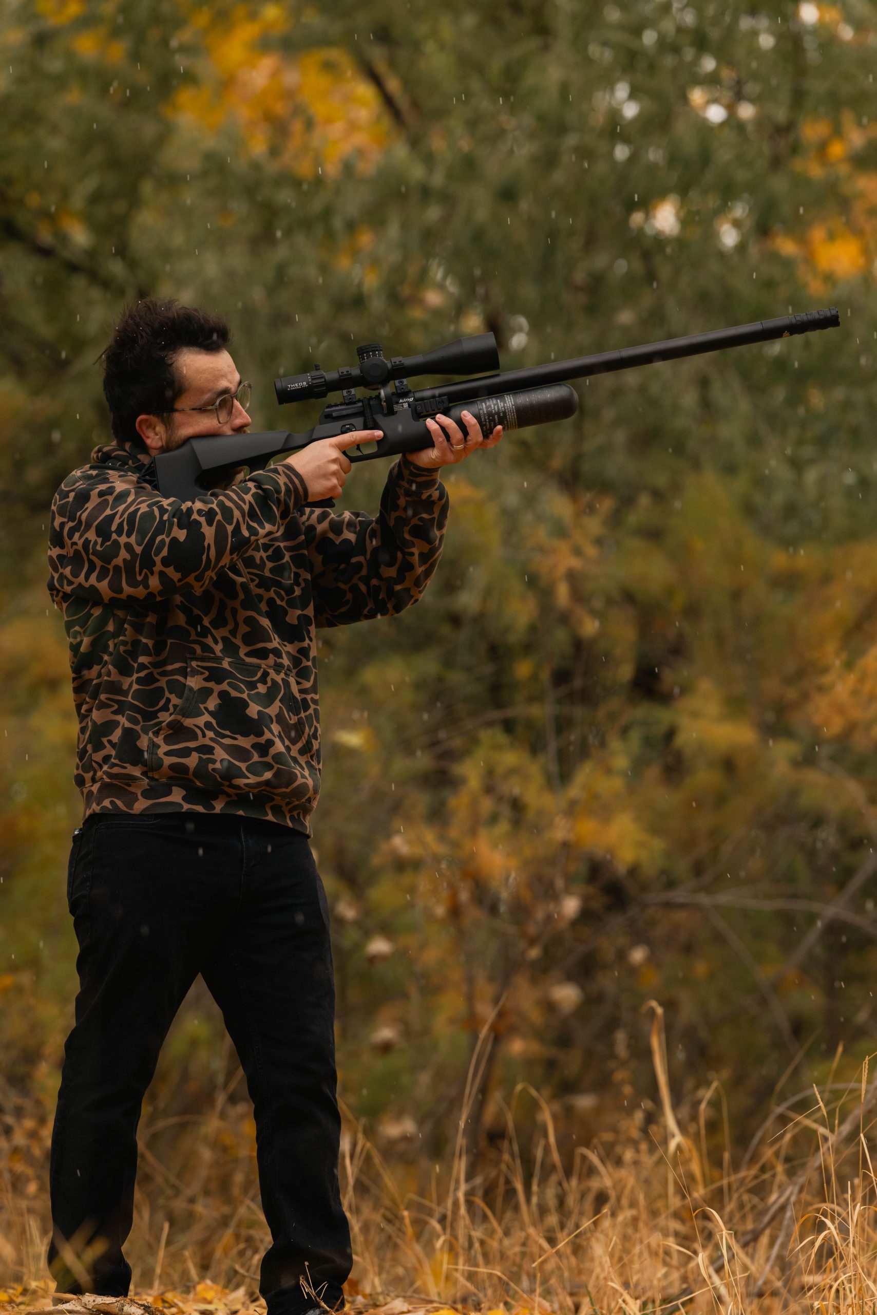 A man standing and shooting an air rifle