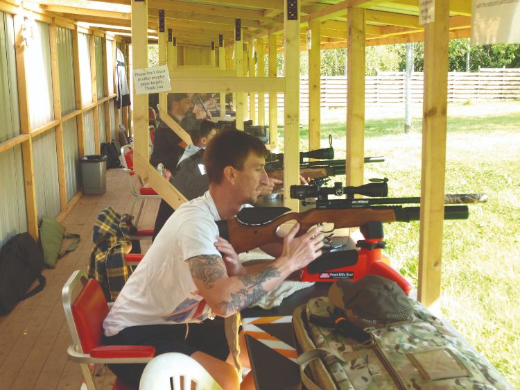 A young man shooting an air rifle in a covered shooting range in the UK