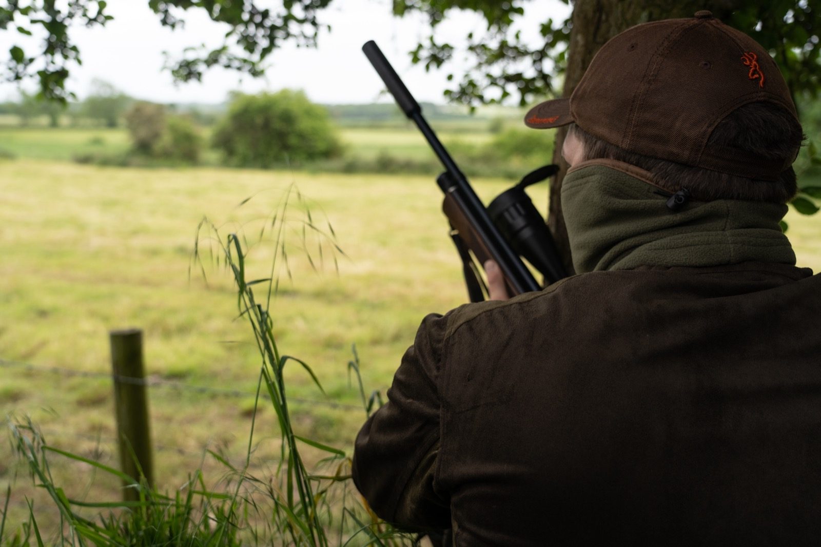 Airgunner taking aim with a scoped, silenced air rifle during grey squirrel control
