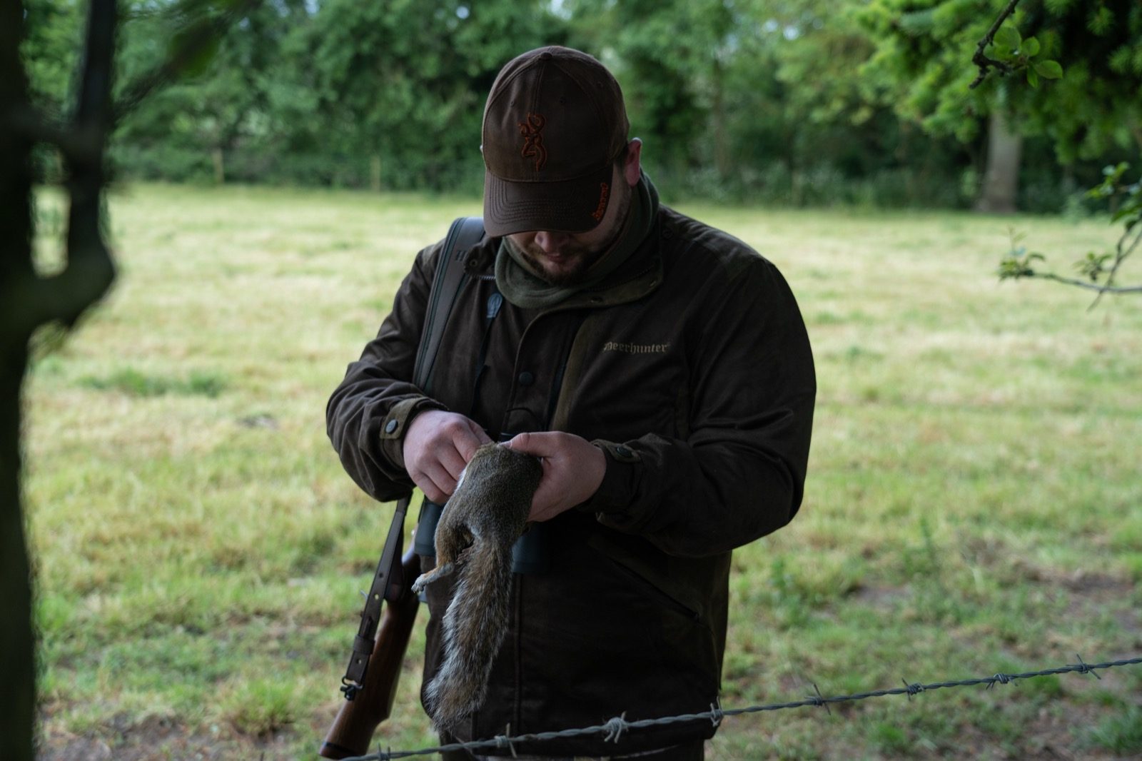 Airgunner inspecting a grey squirrel taken with an air rifle on a woodland permission