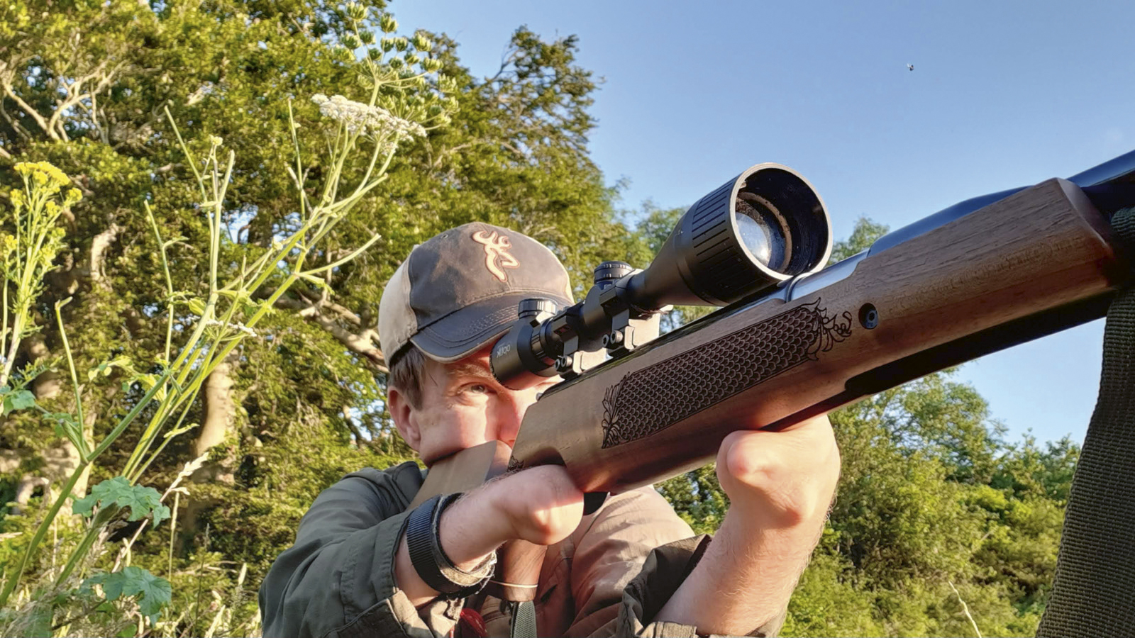 Airgun shooter taking aim with a wood-stocked springer air rifle outdoors