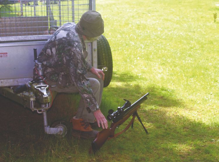 An airgun shooter keeping his gun out of the sunlight